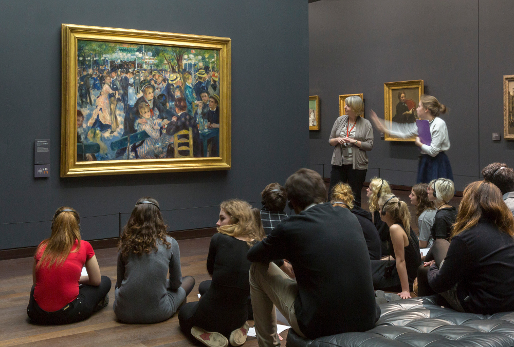 Une intervenante commente le Bal du moulin de la Galette d’Auguste Renoir au musée d’Orsay