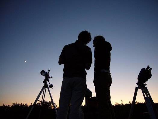 2 téléscopes et 2 personnes à contrejour sur fond de crépuscule sans nuage