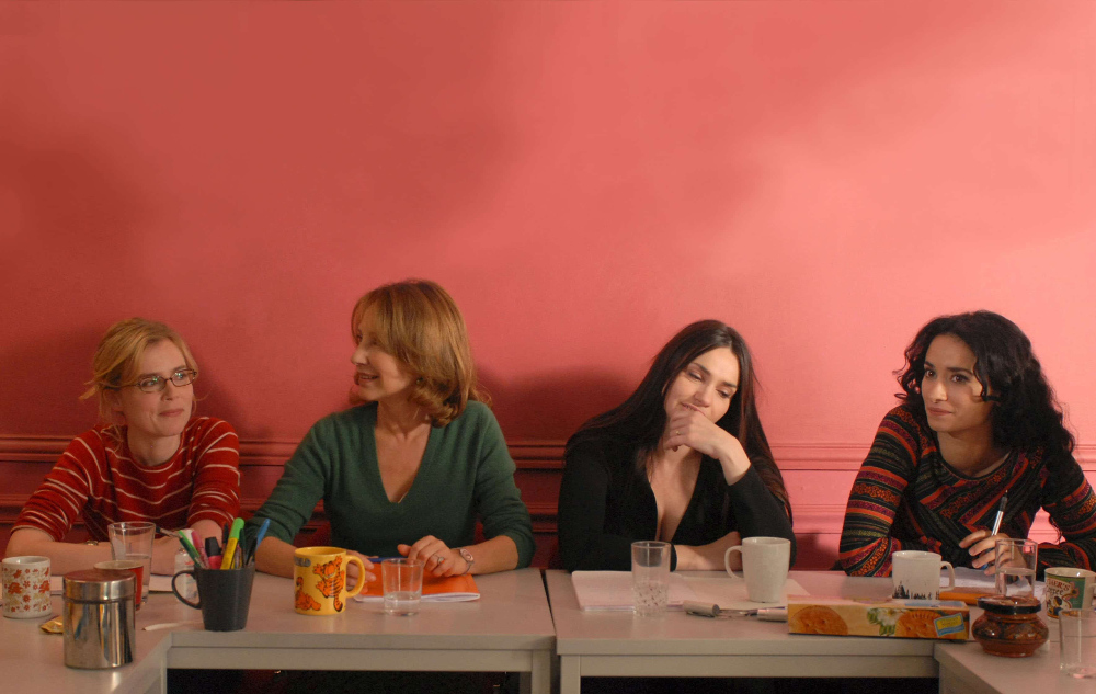 4 femmes assises à une table sur fond rouge