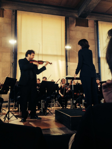 Mme Gibault, de dos, dirige le PMO et un violon soliste au palais d’Iéna