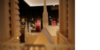 Vue de l’exposition : haut d’une maquette au premier-plan, des panneaux en arrière-plan