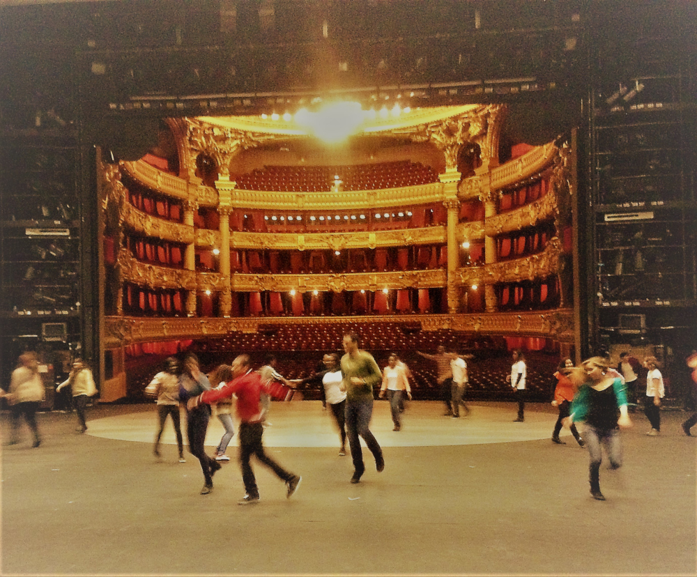 Vue du fond de la scène de l’opéra Garnier, les élèves sont en mouvement sur la scène