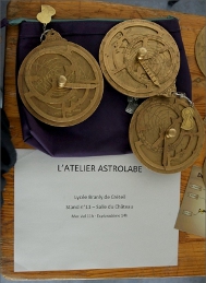 3 astrolabes au-dessus d’une affichette ‘L’atelier astrolabe’